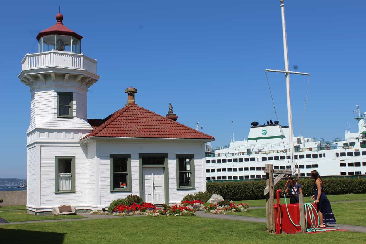 Girls standing in front of well near Mukilteo Lighthouse with Ferry in background