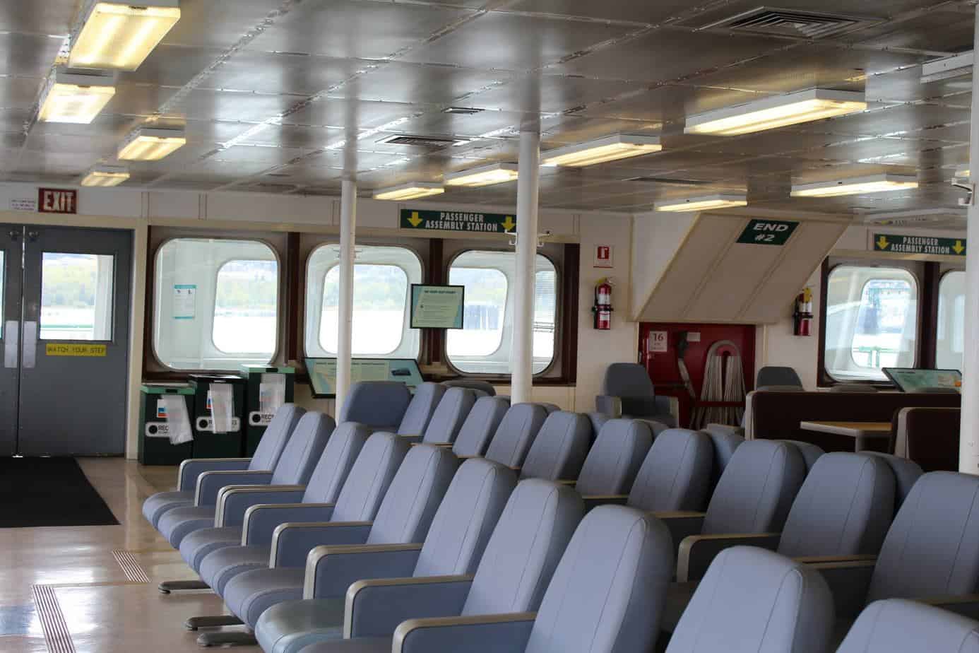 Inside ferry- rows of chairs and rounded square windows in the background