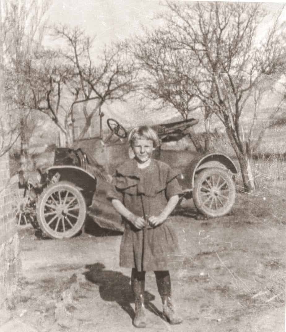 Clara Christensen as a girl in front of old fashioned car