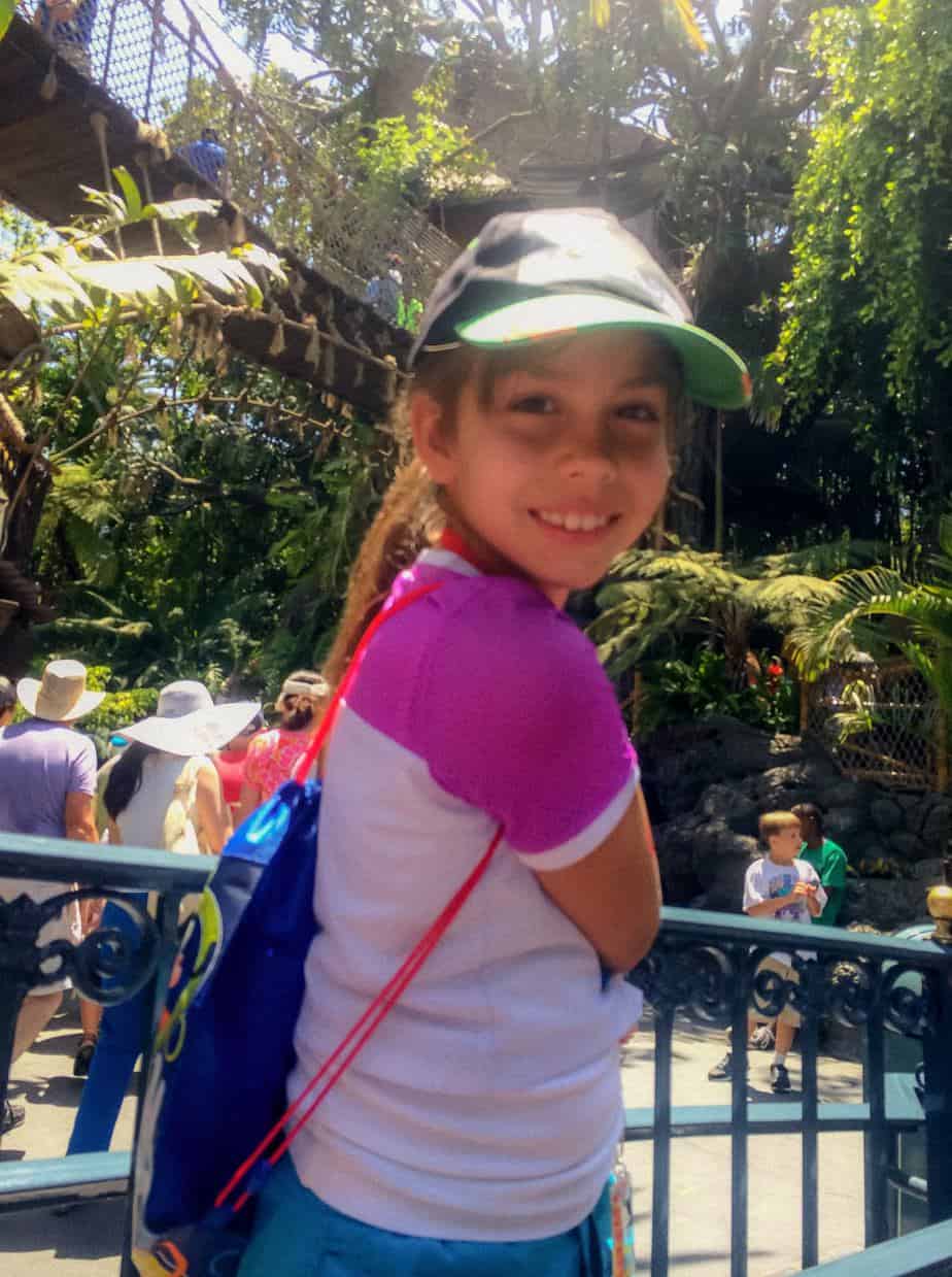 Girl smiling wearing hat and Get Away Today drawstring bag at Disneyland